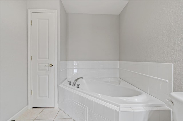 bathroom with tile patterned flooring, toilet, and tiled bath