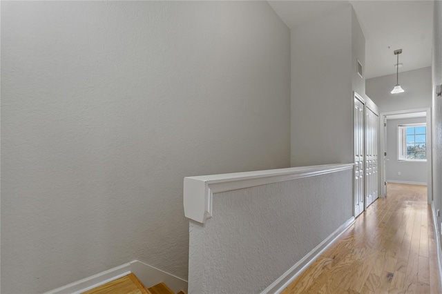 hall with light hardwood / wood-style floors and lofted ceiling