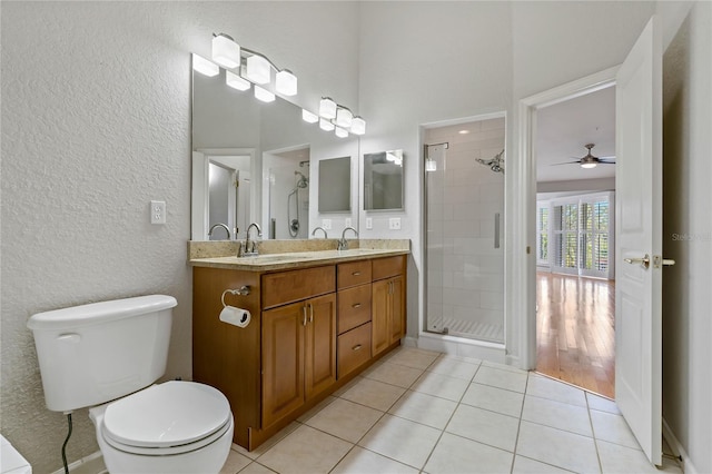 bathroom with tile patterned floors, ceiling fan, a shower with door, and vanity