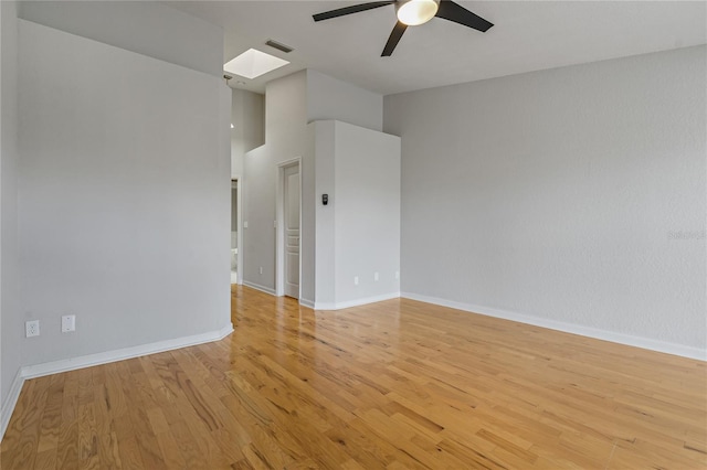 empty room featuring light wood-type flooring, a skylight, and ceiling fan