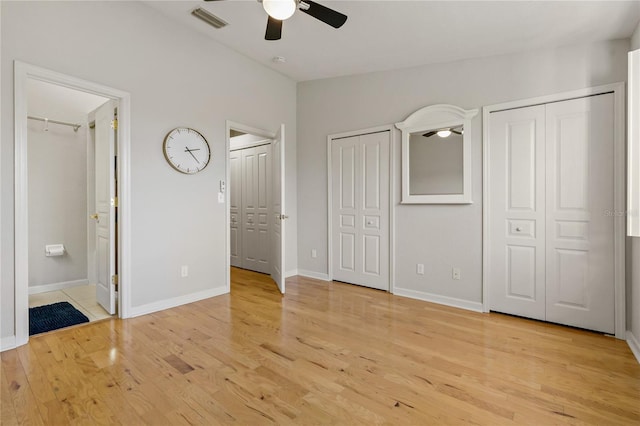 unfurnished bedroom with ceiling fan, ensuite bathroom, two closets, and light wood-type flooring