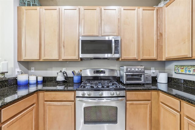 kitchen with dark stone countertops, light brown cabinets, and stainless steel appliances