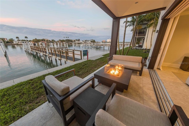 patio terrace at dusk with an outdoor fire pit, a dock, and a water view