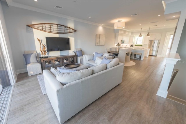 living room featuring light wood-type flooring and ornamental molding