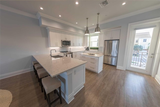 kitchen with stainless steel appliances, sink, white cabinetry, and decorative light fixtures