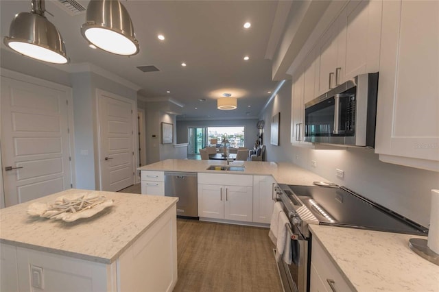 kitchen featuring stainless steel appliances, white cabinetry, a kitchen island, and decorative light fixtures