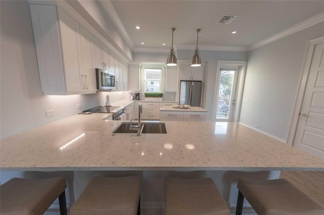 kitchen featuring appliances with stainless steel finishes, white cabinetry, sink, hanging light fixtures, and ornamental molding