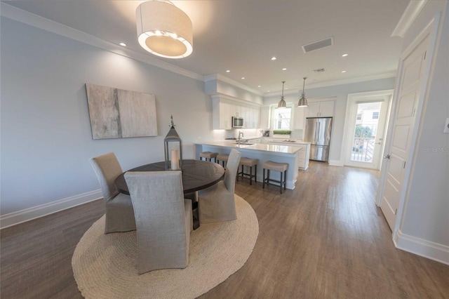 dining room featuring dark wood-type flooring, ornamental molding, and sink