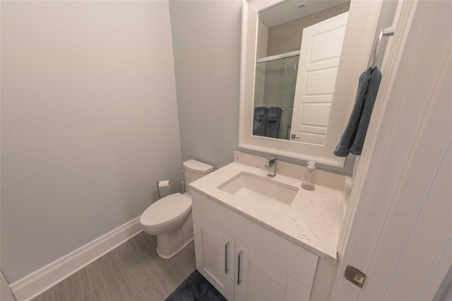 bathroom featuring toilet, hardwood / wood-style flooring, an enclosed shower, and vanity