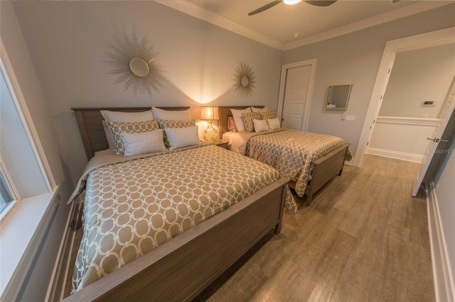 bedroom featuring ceiling fan, ornamental molding, and wood-type flooring