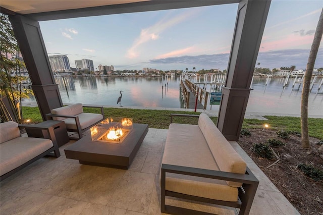 patio terrace at dusk featuring a water view and a fire pit