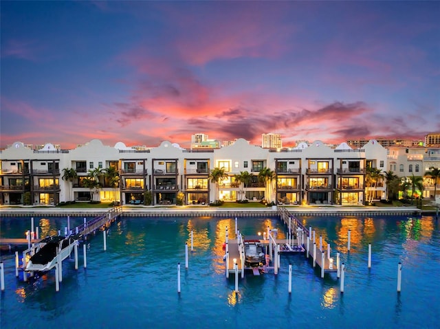 pool at dusk featuring a water view and a dock