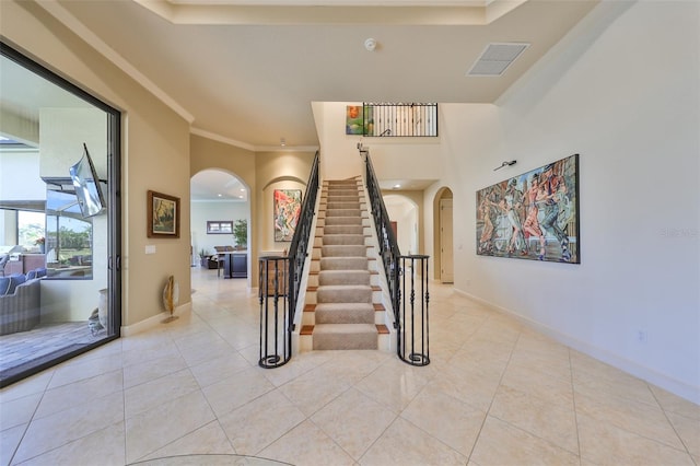 staircase with ornamental molding and tile patterned flooring