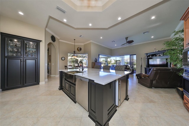 kitchen with ceiling fan, a center island with sink, stainless steel dishwasher, a breakfast bar, and sink