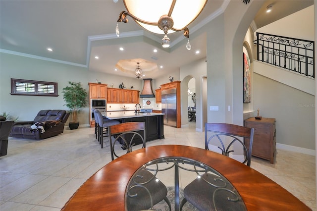 tiled dining space featuring crown molding, sink, and a tray ceiling