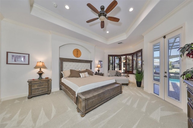 bedroom featuring ceiling fan, access to exterior, a tray ceiling, and multiple windows