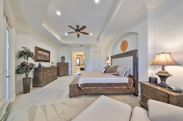 carpeted bedroom featuring ceiling fan, ensuite bath, a tray ceiling, and ornamental molding