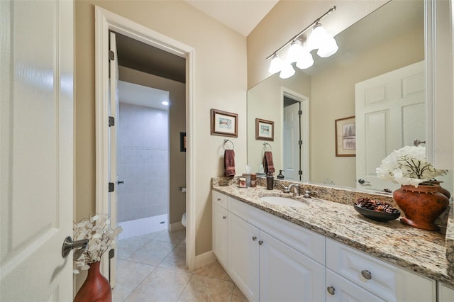 bathroom with tiled shower, tile patterned floors, vanity, and toilet