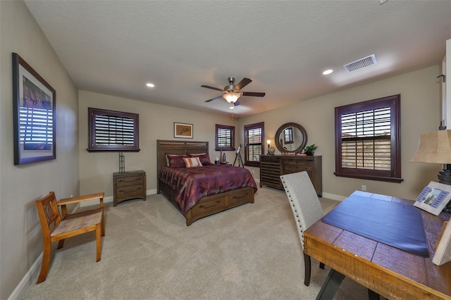 bedroom with ceiling fan, a textured ceiling, and light carpet