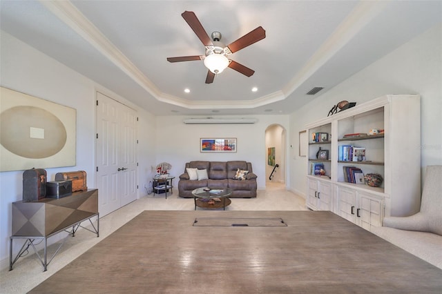 living room featuring ceiling fan, light colored carpet, a raised ceiling, a wall mounted air conditioner, and ornamental molding