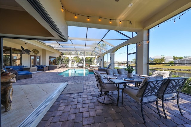 view of pool featuring glass enclosure, ceiling fan, an outdoor hangout area, and a patio