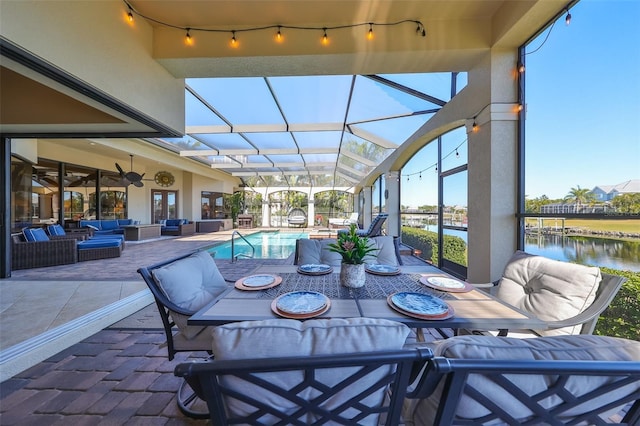 view of patio / terrace featuring ceiling fan, a lanai, an outdoor hangout area, and a water view