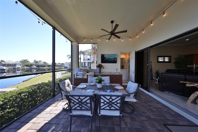 sunroom with ceiling fan, sink, and a water view