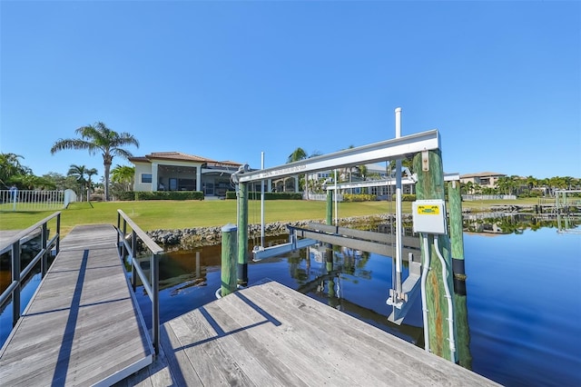 view of dock with a lawn and a water view