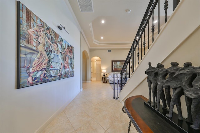 corridor with light tile patterned floors, crown molding, and a tray ceiling