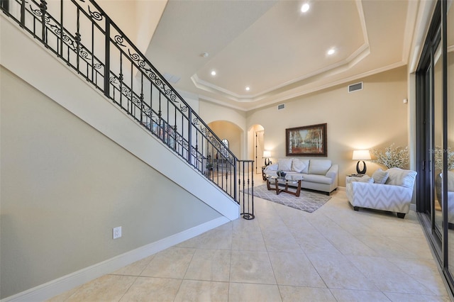 staircase with ornamental molding, tile patterned floors, and a raised ceiling