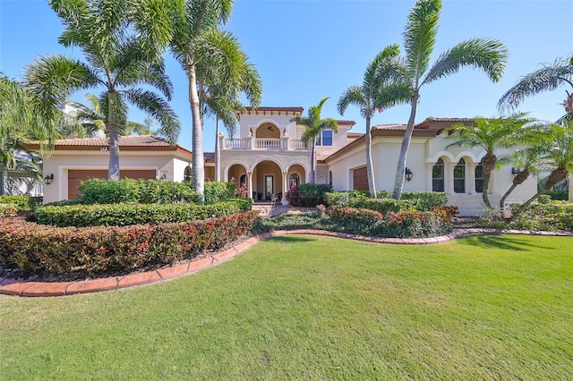 mediterranean / spanish-style home featuring a front yard, a balcony, an attached garage, and stucco siding