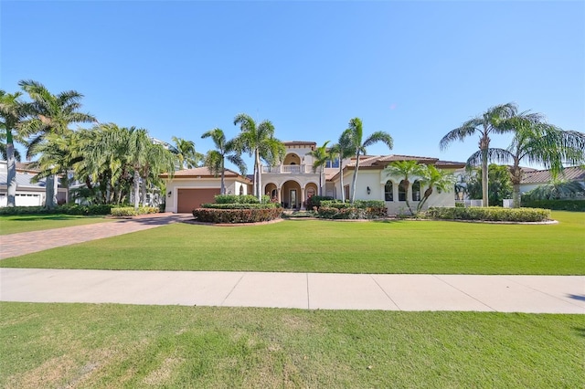 mediterranean / spanish house with decorative driveway, an attached garage, and a front lawn