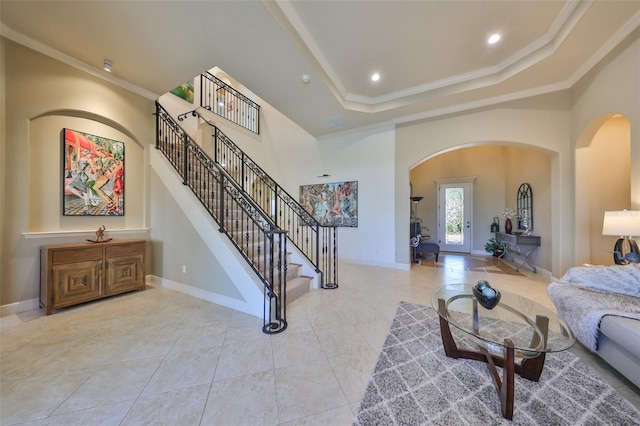 living area with baseboards, a high ceiling, a tray ceiling, stairs, and crown molding