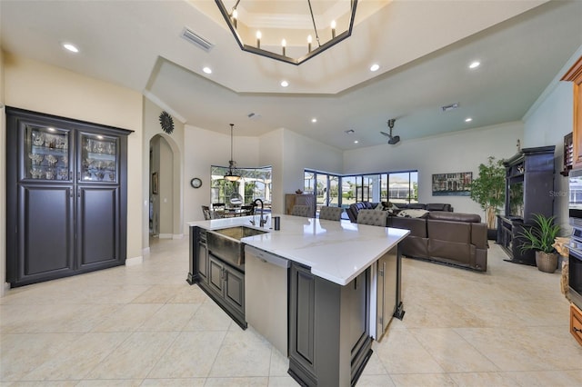 kitchen with a tray ceiling, a sink, stainless steel dishwasher, and crown molding