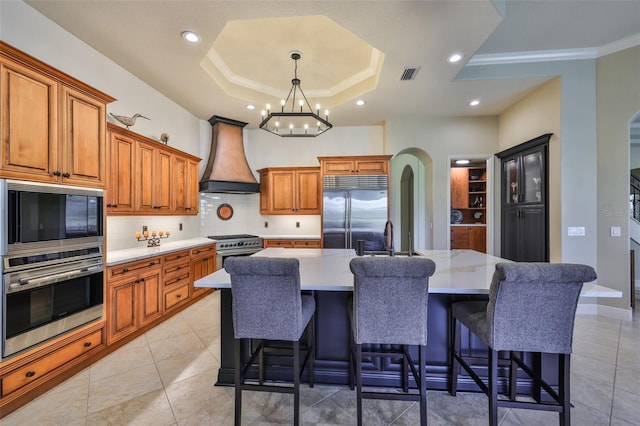 kitchen featuring a sink, visible vents, brown cabinets, high end appliances, and custom range hood