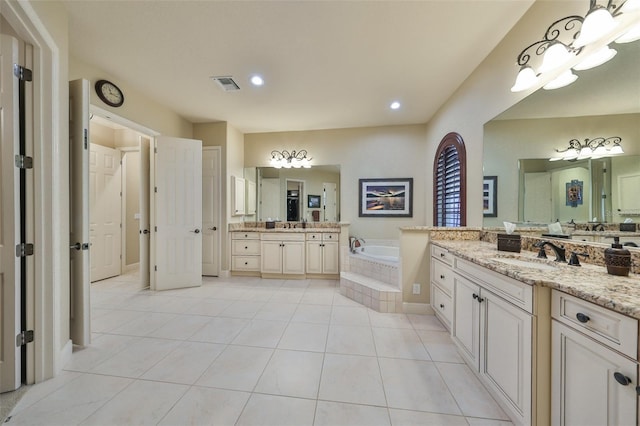 bathroom featuring visible vents, two vanities, tile patterned floors, a sink, and a bath