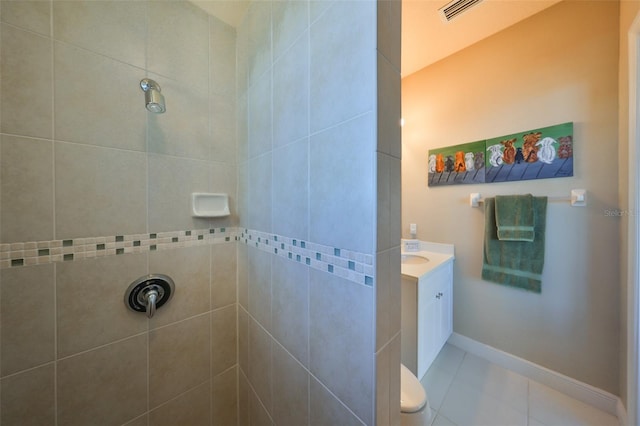 bathroom featuring visible vents, a tile shower, vanity, baseboards, and tile patterned floors