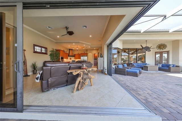 living area featuring a skylight, a ceiling fan, visible vents, and crown molding