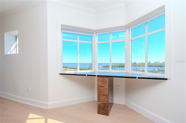 interior space featuring hardwood / wood-style floors, a water view, ornamental molding, and built in desk