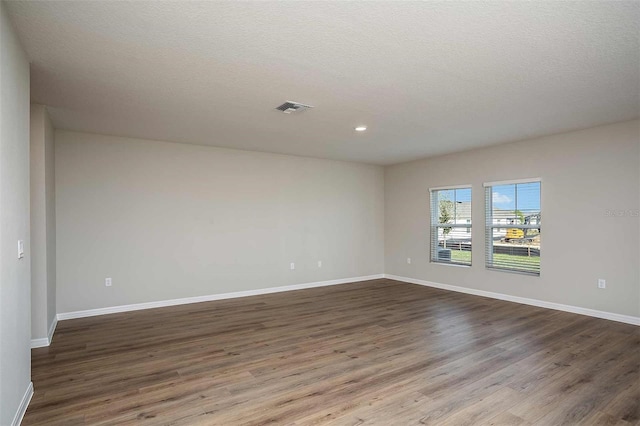 empty room with a textured ceiling and hardwood / wood-style flooring