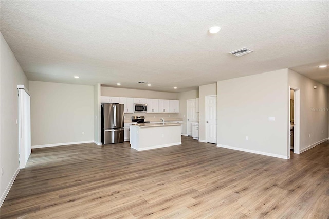 unfurnished living room featuring a textured ceiling and light hardwood / wood-style flooring