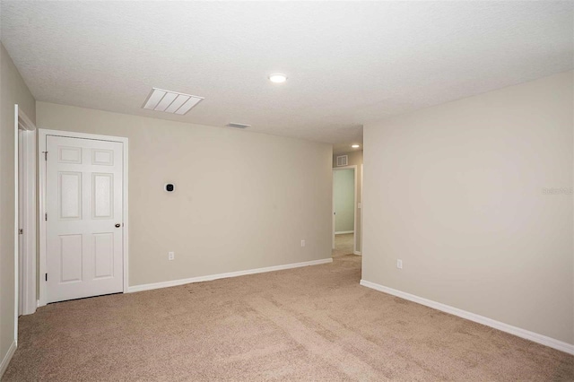 empty room with light carpet and a textured ceiling