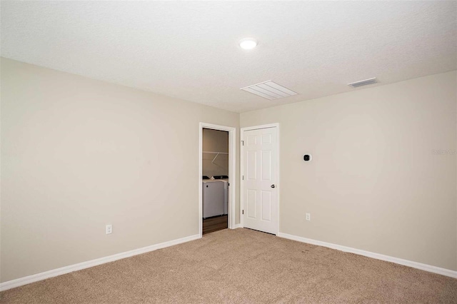 spare room with separate washer and dryer, light carpet, and a textured ceiling