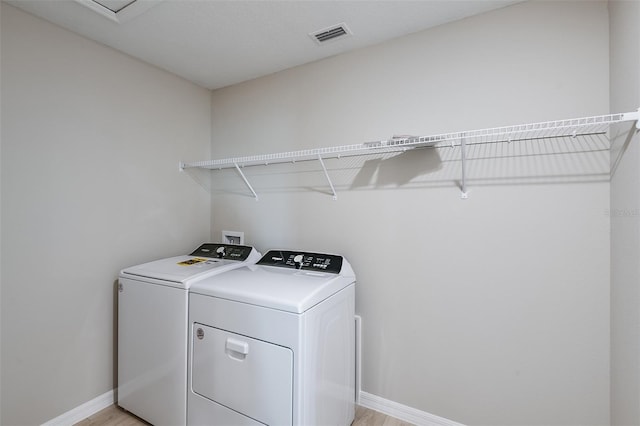 washroom featuring washer and clothes dryer and light hardwood / wood-style flooring