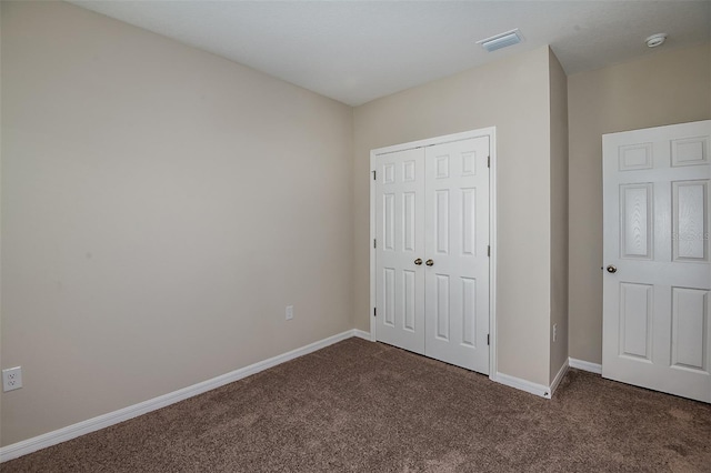 unfurnished bedroom featuring dark carpet and a closet