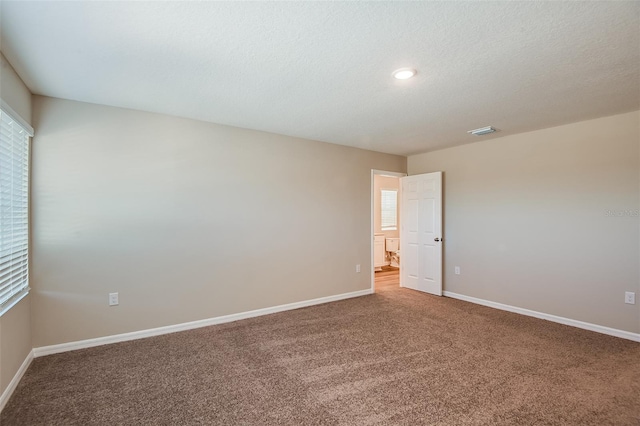 spare room featuring carpet flooring and a textured ceiling