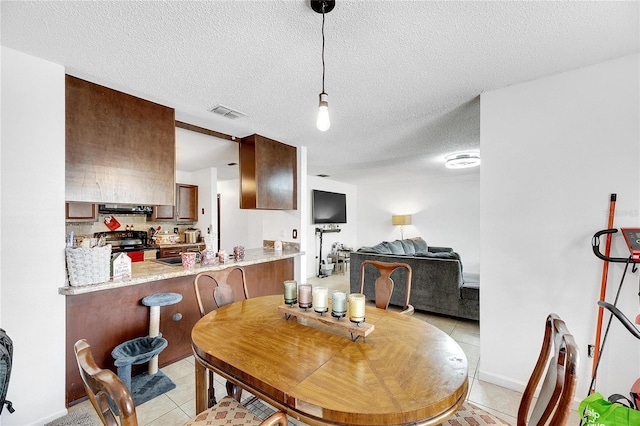 dining space featuring light tile patterned flooring and a textured ceiling