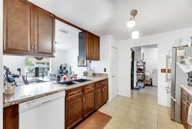 kitchen featuring sink, hanging light fixtures, stainless steel fridge, white dishwasher, and light tile patterned floors