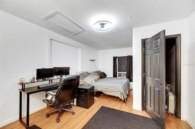 bedroom featuring a textured ceiling and light hardwood / wood-style flooring