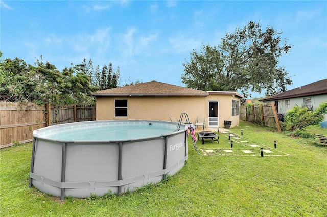 rear view of property featuring a fire pit, a fenced in pool, and a yard